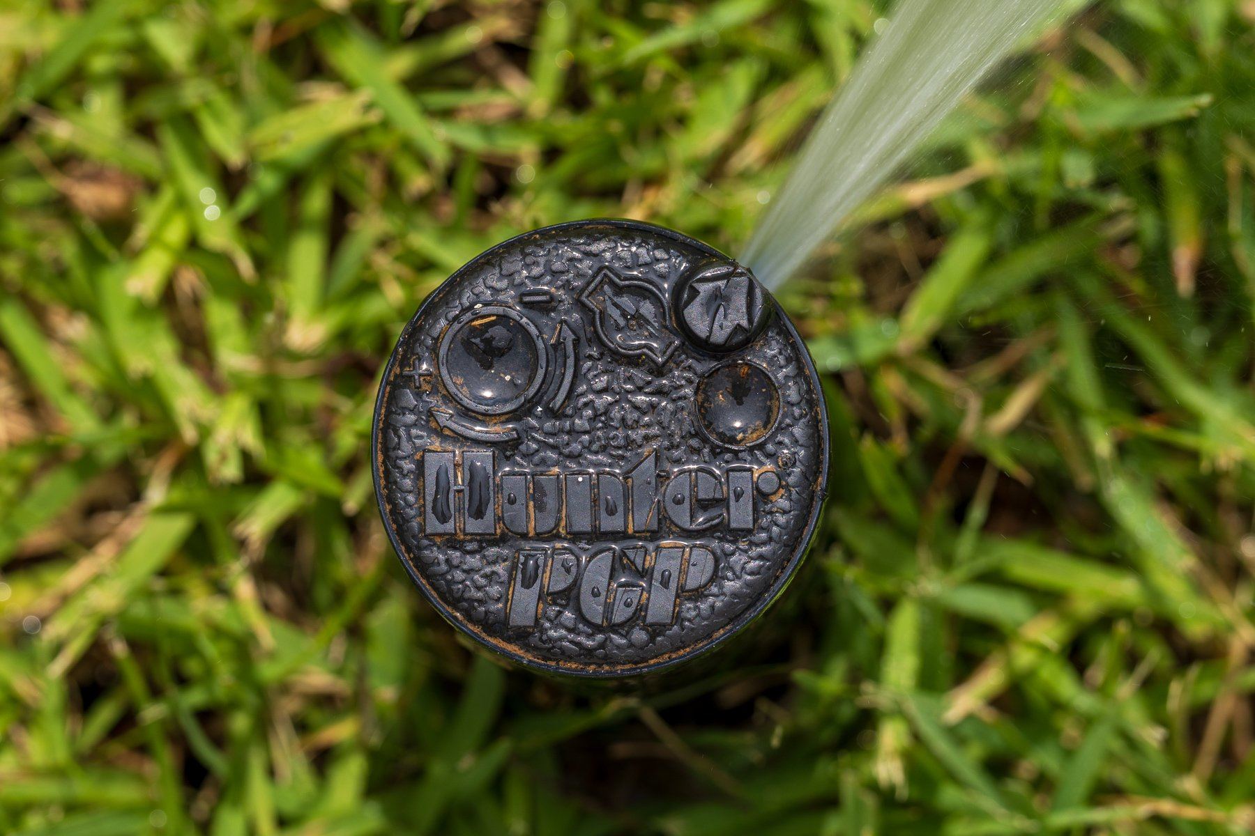 Close-up of a rotor head spraying in the grass