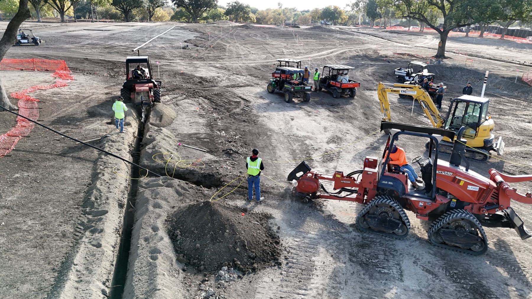 Crew trenching irrigation lines across a golf course renovation
